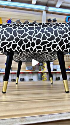 a giraffe print foot stool sitting on top of a wooden floor next to shelves