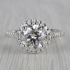 an engagement ring with a large diamond surrounded by small diamonds on the band and sidestones