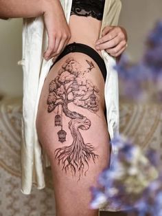 a woman with a tree tattoo on her thigh