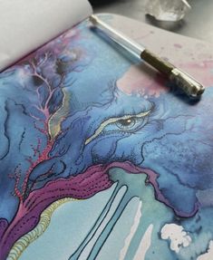 a pen is sitting on top of an art work with watercolors and ink