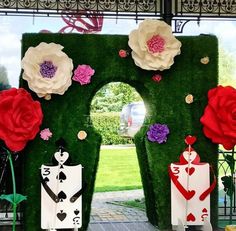 an entrance decorated with fake flowers and playing cards in front of a green lawn area