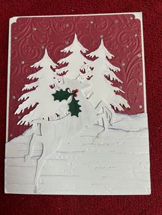 a christmas card with white snow and trees on the front, red paper background that says merry