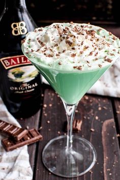 a green drink in a martini glass with whipped cream and chocolate sprinkles