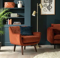 two orange chairs in a living room with blue walls