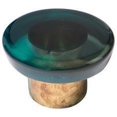 a green and gold pedestal with a circular glass top on the base, against a white background