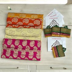 four different colored bags sitting on top of a counter next to some papers and envelopes