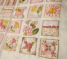 a white table cloth with pink and yellow embroidered designs on it, along with a button