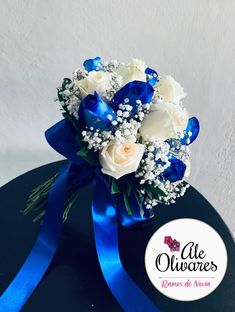 a bouquet of white and blue flowers on top of a black box with a blue ribbon