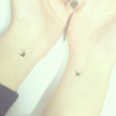 two small birds on their wrist tattoos are seen in this image, one is black and the other is white