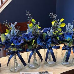 three vases filled with blue flowers on top of a table