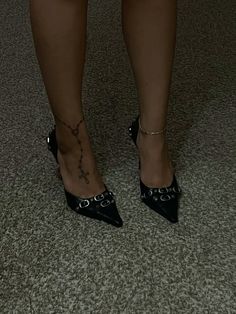 a woman's legs wearing black high heels with chains on the ankles and ankle