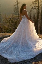 a woman in a white wedding dress standing on top of a mountain with trees behind her