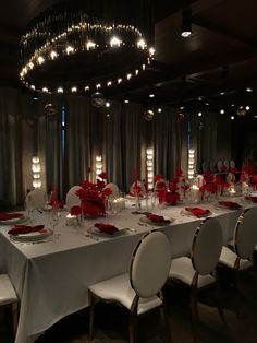 a dining room set up with white table cloths and red flowers