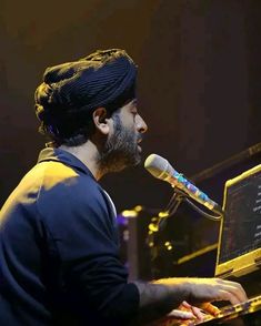 a man sitting at a piano with a microphone in front of him and playing the keyboard