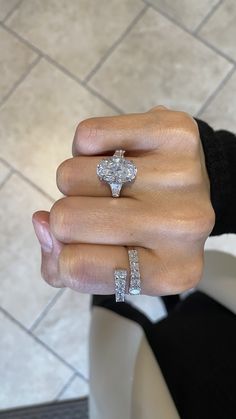 a woman's hand with two engagement rings on her left and the middle finger