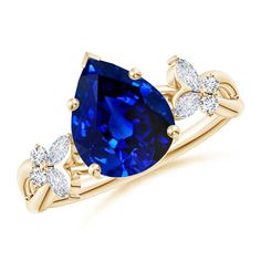 a yellow gold ring with an oval blue sapphire and two pear shaped diamonds on the band