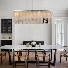 a dining room table with chairs and a chandelier hanging from it's ceiling