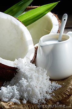 coconuts and sugar are sitting on a table next to some green leaves with a spoon in them