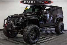 a black jeep is parked in front of a sign that says rubitrax