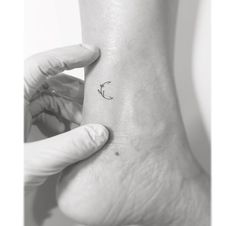 a person's foot with a small tattoo on the left side of their ankle