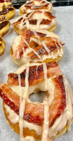 bacon donuts with white glaze and icing are lined up on a table