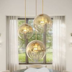 three glass balls hanging from the ceiling above a dining room table with white linens