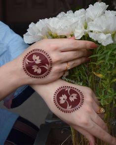 two hands with henna tattoos on their palms and white flowers in front of them