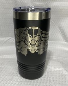 a tumbler cup with a skull and barbells on the side, sitting on a white background