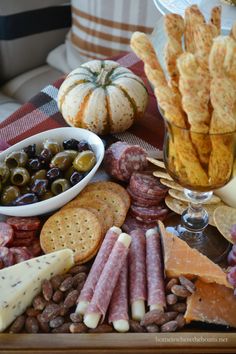 an assortment of cheeses, crackers, olives and meats on a platter