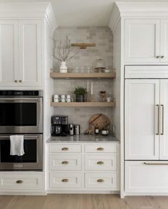 a kitchen with white cabinets and stainless steel stove top oven, built - in shelving