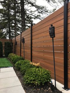 a wooden fence next to a sidewalk and trees