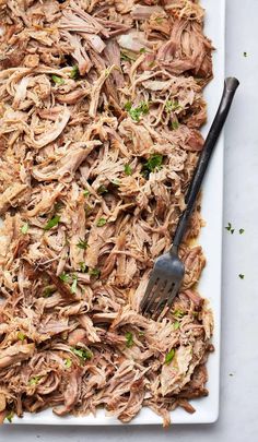 shredded pork on a white plate with a fork