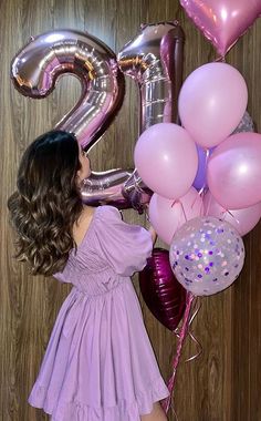 a woman in a purple dress is holding some balloons and the number twenty five balloon