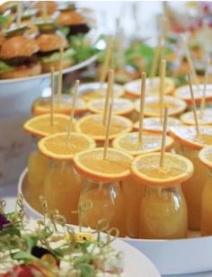 orange slices and strawberries are arranged on the trays with toothpicks in them