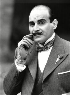 an old photo of a man in a suit and bow tie holding his finger to his mouth