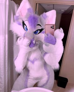 a white and purple cat taking a selfie in front of a mirror with a cell phone