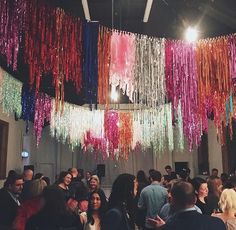 a large group of people are gathered in a room with streamers hanging from the ceiling