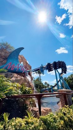 an amusement park with a roller coaster in the foreground and a blue sky above it