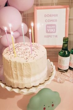 a birthday cake with candles on it and some balloons in the back ground behind it