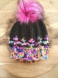 a multicolored beanie with a pink pom - pom on top