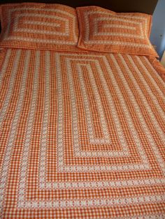 an orange and white checkered bedspread on a bed with two night stands