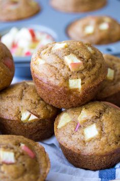 several muffins are stacked on top of each other with apples in the background