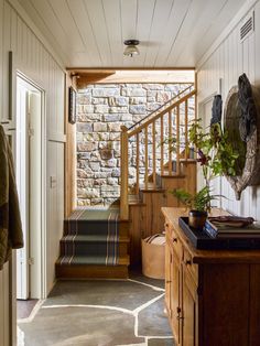 an entryway with stone walls and wooden steps leading up to the second floor area