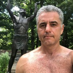 a man with no shirt standing in front of a statue