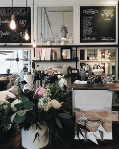 flowers in a white bucket sitting on a table next to a menu and coffee machine