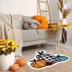 a living room filled with furniture and decor on top of a hard wood floor covered in fall decorations