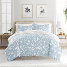 a bed with blue and white comforters in a room next to two pictures on the wall