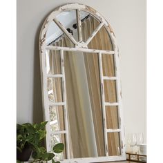 a mirror sitting on top of a dresser next to a potted plant and vase