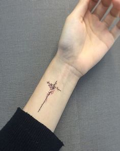 a woman's wrist with a small cross tattoo on the left side of her arm