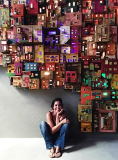 a woman sitting on the ground in front of a wall made out of blocks